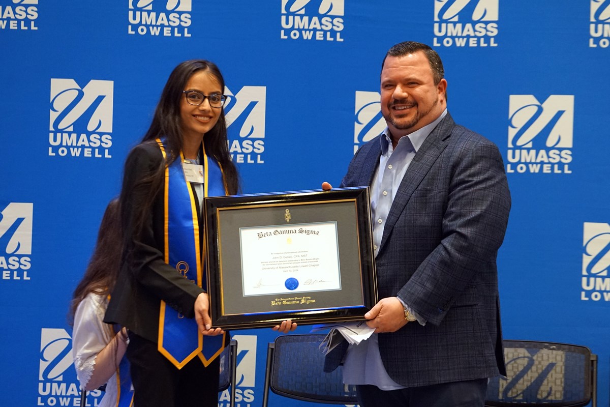 Two people pose for a photo while holding a framed certificate.